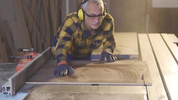 timmerman werken met zag in werkplaats. volwassen timmerman hakken hout in werkplaats. video