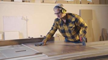 adulto carpintero cortes madera en el carpintería tienda. carpintero hombre es corte madera en taller. video