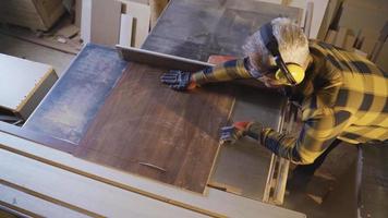 volwassen timmerman zijn gebruik makend van tafel zag naar besnoeiing in timmerwerk winkel. volwassen timmerman toepassingen tafel zag naar besnoeiing hout in timmerwerk winkel. video