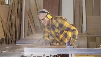 The carpenter uses the table saw and cuts the boards. Carpenter man using chainsaw cuts boards. video