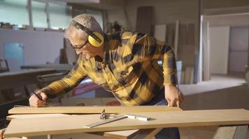 hout bord meting in een timmerwerk winkel. mannetje timmerman meten hout met meter en markering met potlood. video