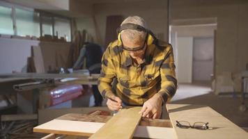 medida madera. el carpintero medidas el tablero con el metro. masculino carpintero medición madera con metro y calificación con lápiz. video