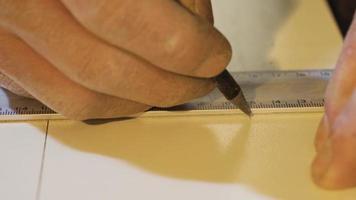 charpentier mains les mesures le planche avec une règle et Des marques il avec une crayon. Sénior Charpentier mains mesure une bois avec une règle dans atelier.