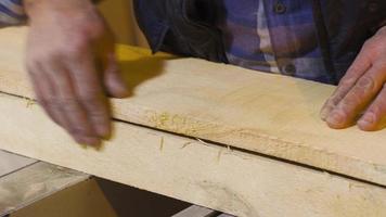 Charpentier Maître caressant brut bois avec le sien mains. employé qui aime le sien emploi. Charpentier choisit en bois planche dans charpenterie magasin. charpenterie, savoir-faire concept. video
