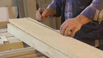 Sénior Charpentier les mesures bois par mètre dans atelier. fermer de froissé Charpentier mains mesure bois avec mètre. video