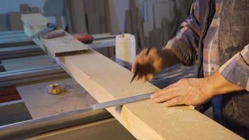 Carpenter cuts timber with handsaw in carpentry workshop. Carpenter man cutting the lumber he measured by the meter with a handsaw. video