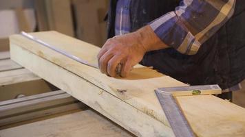 Close-up of crumpled carpenter hands measuring wood with meter. Senior carpenter hands measure raw wood with ruler and mark with pencil. video