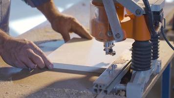 il falegname fa il cerniera fori nel il truciolare con acuto coltelli. falegname perforazione legna con coltelli nel piatto nel carpenteria officina. video