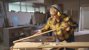 Carpentry Workshop. The carpenter takes measurements from wood with a meter. video