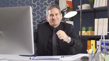 Confident handsome mature middle aged businessman. Mature businessman sitting happily at his desk and looking at camera rejoicing. video