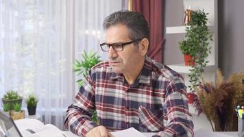 Businessman with glasses works carefully and intensely in his home office. Businessman in glasses working in home office looking at laptop, conducting busy and careful business. video