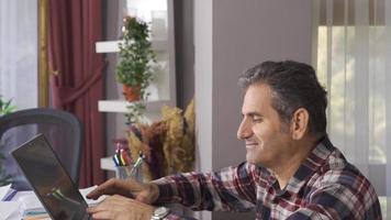 Happy mature man working in home office. The mature man has completed his work and is happy. video