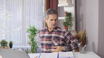 The man with a backache from working hard. The man sitting in the chair for a long time tries to stand up and sits down again by holding his waist. video