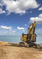 excavadora sobre orugas después de las obras en el sitio de construcción en la playa del mar foto