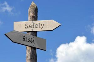 Safety and Risk - Wooden Signpost with Two Arrows, Sky with Clouds photo