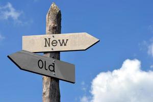 Old or New - Wooden Signpost with Two Arrows, Sky with Clouds photo