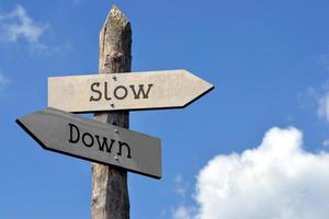 Slow Down - Wooden Signpost with Two Arrows, Sky with Clouds photo