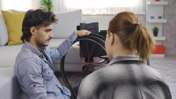 depresso Disabilitato giovane uomo e il suo fidanzata siamo chat a casa. Disabilitato uomo utilizzando un' sedia a rotelle e il suo fidanzata siamo chat a casa, il Disabilitato uomo è infelice. video