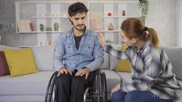 discapacitado masculino hombre en silla de ruedas chateando con amigo a hogar. su Novia quien apoyos el discapacitado hombre quien es en un malo humor. aumento conciencia. video