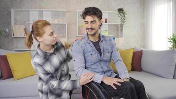 Happy disabled man and his girlfriend having fun at home. Disabled man in wheelchair and his girlfriend at home chatting, joking and having fun. video