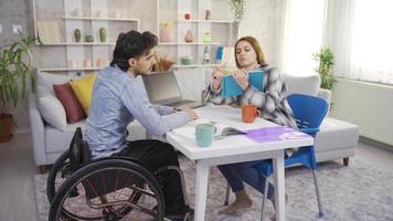 a hogar el discapacitado hombre y su Novia son estudiando para lecciones beca. un estudiante con un invalidez y un joven niña Mira a un ordenador portátil y libros a hogar. video