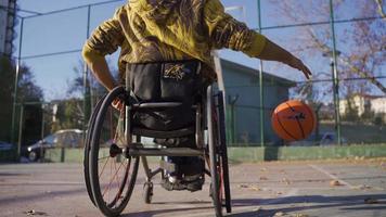 désactivée homme en jouant basketball dans une fauteuil roulant, dribble le balle. désactivée homme dans fauteuil roulant dribble sur basketball tribunal et pousse dans le panier. video