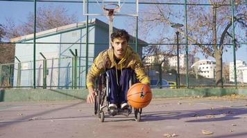 minusválido baloncesto jugador en un silla de ruedas regate me gusta un profesional. silla de ruedas atleta joven hombre practicando baloncesto y regate pelota en mano. video