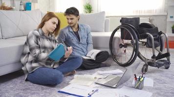 Student girl and disabled young man study at home. Student disabled man and his girlfriend study at home. video