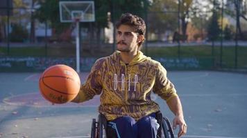 Disabilitato adolescente giocando pallacanestro nel sedia a rotelle nel lento movimento. Disabilitato uomo nel un' sedia a rotelle spara cesti su il pallacanestro Tribunale. video