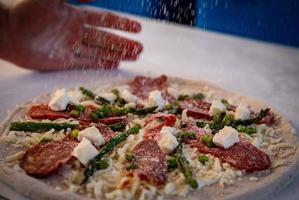 Chef putting parmesan on a pizza photo