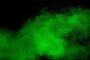 Abstract green powder explosion on black background.Freeze motion of green dust cloud. photo