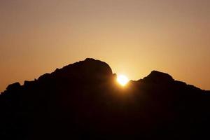 landscape with sun rising behind rocks photo