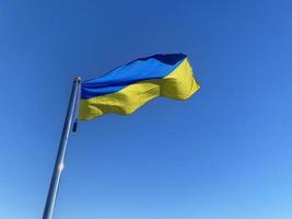 waved Ukrainian flag on flagpole against blue sky photo