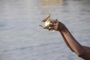 hands of hindu performing morning puja ritual at Ganges river photo