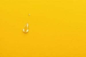 single water drop on yellow plain background, minimalistic design backdrop with copy space photo