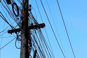 Tangled electrical wires on urban electric pole. Disorganized and messy to organization management concept. Closeup tangled electrical wires . Should take underground wire for beautiful landscape. photo