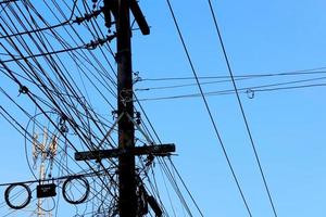 Tangled electrical wires on urban electric pole. Disorganized and messy to organization management concept. Closeup tangled electrical wires . Should take underground wire for beautiful landscape. photo