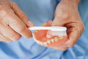 asiático mayor mujer paciente cepillo dientes dentadura con cepillo de dientes para masticar alimento.