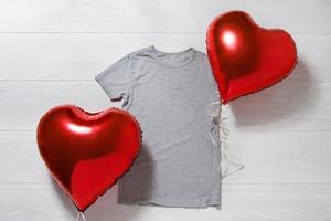 gris camiseta Bosquejo. san valentin día concepto camisa, globos corazón forma en de madera antecedentes. Copiar espacio, modelo blanco frente ver camiseta ropa. romántico atuendo. plano laico cumpleaños fiesta Moda foto