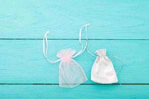 White silver drawstring bag on blue wooden background. Fabric cotton small bag. Jewelry pouch. Top view. Copy space and mock up. photo