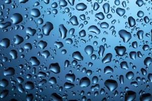 agua gotas en vaso en un azul antecedentes. foto