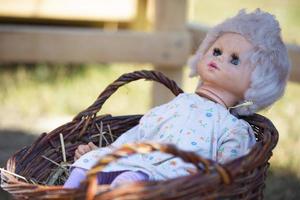 antiguo retro muñeca en un mimbre cesta. foto