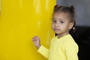 retrato de un pequeño africano americano niña en un amarillo antecedentes. foto