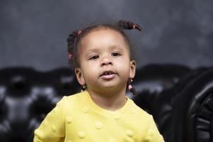 Portrait of a little playful African American girl on a dark background. photo