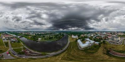 aerial seamless spherical 360 hdri panorama overlooking old town, historic buildings with bridge across wide river with dark sky with storm black clouds in equirectangular projection. vr ar content photo