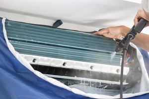 Servicio de limpieza de aire acondicionado con spray de agua. foto