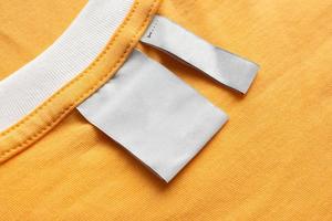 Blank white laundry care clothes label on yellow fabric texture background photo