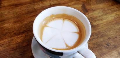 cerca arriba blanco taza de caliente latté Arte en flor o hojas dibujo en oscuro marrón de madera antecedentes o mesa con Copiar espacio. refresco Bebiendo y comida diseño concepto foto