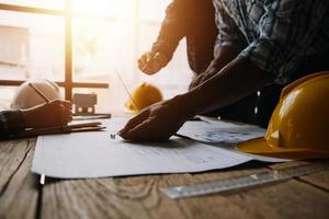 construcción y estructura concepto de ingeniero trabajando dibujo en Plano reunión para proyecto trabajando con compañero en modelo edificio y Ingenieria herramientas en trabajando sitio, construcción concepto foto