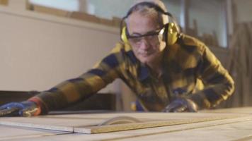 fabricante adulto carpintero cortes madera en el carpintería taller. productivo carpintero corte madera en Sierra para nuevo productos video